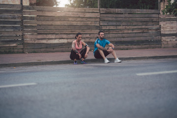 Fit couple rest after running and sit on the street.