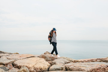 Fototapeta premium A traveler in a hat with a backpack walks next to the sea. Travel, tourism, freedom.