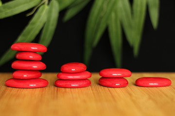 Pierre galet rouge posés sur un sol de bois et emplilés sur plusieurs colonnes en mode de vie zen sur fond noir