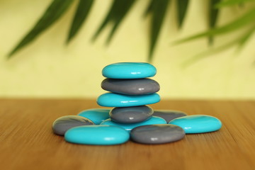 Pierre galet bleu et gris posés sur un sol de bois et emplilés en mode de vie zen sur fond vert