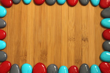 petits galets rouge gris et bleu disposé tout autour d'un plancher de bois de bambou marron avec un espace vide pour écrire un message