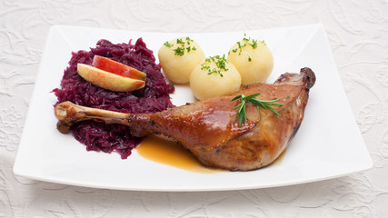 Gänsekeule mit Apfelrotkohl und Klößen - Festtagsessen auf weißer Tischdeck