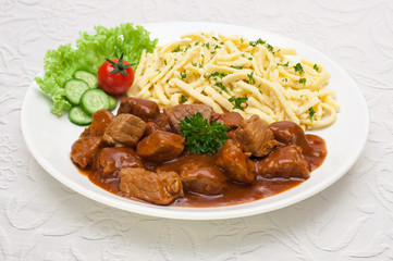 Gulasch mit Spätzle - Tellergericht auf weißer Tischdecke