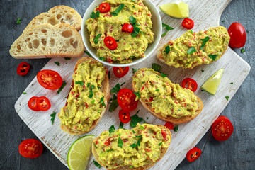Homemade Guacamole toast with chili pepper, parsley on white wooden board