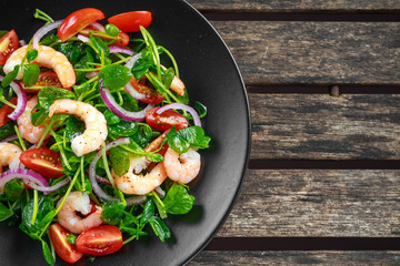 Fresh Healthy Prawns salad with tomatoes, red onion on black plate. concept healthy food