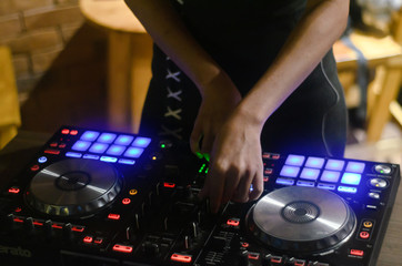 Obraz premium Hands disc jockey at the turntable. DJ plays on the best, famous CD players at nightclub during party. EDM, party concept.