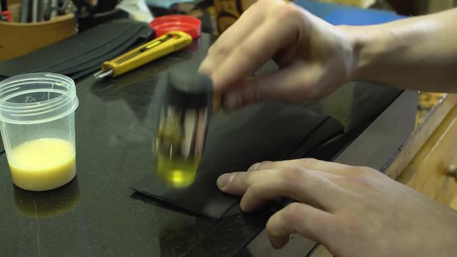 The skinner taps the hammer with a hammer over the glued leather product close-up 4k.