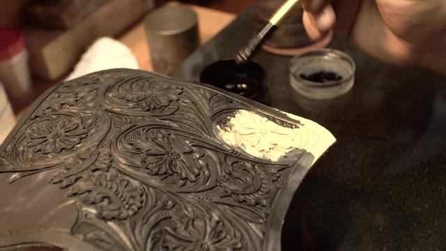 Bearded skinner covers a piece of leather with embossed flowers close-up 4k.