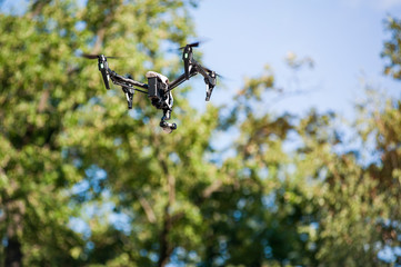 Flying drone in forest.Selective focus/Modern drone with camera hovering in air against background of trees