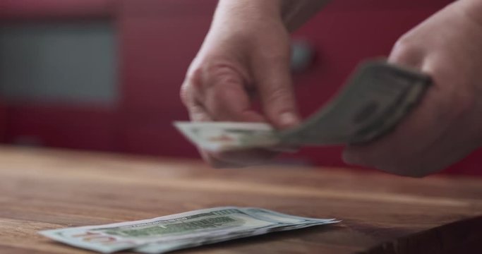 slow motion side shot of woman counting dollars on wood table