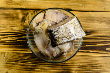 Pieces of the marinated carp in bowl on wooden table. Top view