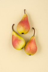 Three ripe pears on a light yellow pastel background..