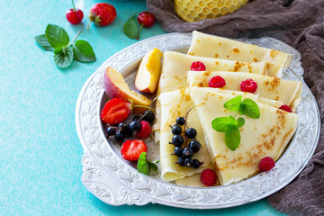 Pancake breakfast with honey and fresh berries of currants, strawberries, nectarines, sweet cherries and raspberries.