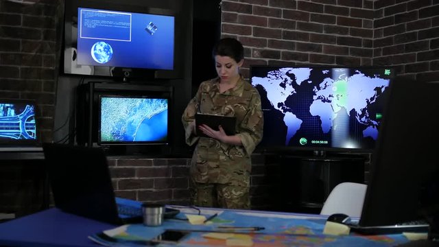 portrait woman soldier with tablet, against background electronic monitors, cyber safety, technical control, tracking system, military staff, attack and security, control center, war base, IT war,