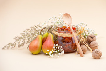 Still life with pear jam, pears, dried herbs and walnuts on a light beige background..
