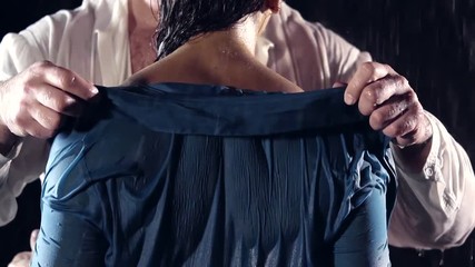 close-up. male hands removed the wet clothes from her shoulder to expose the back. muscular back girl athlete. people in the rain night