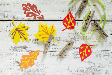 Autumn background with colorful different leaves of paper and wooden clothespins on a wooden...