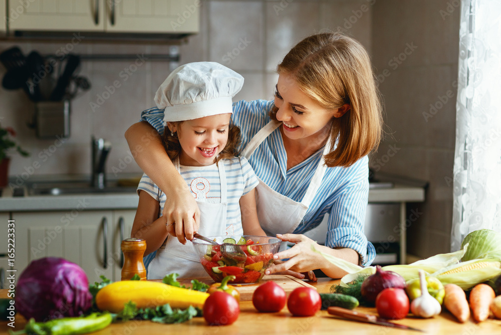 Wall mural healthy eating. family mother and child girl preparing vegetarian vegetable salad at home in kitchen