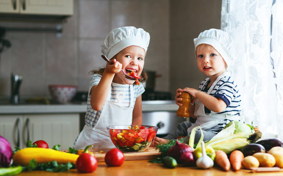 Healthy eating. Happy children prepares  vegetable salad in kitchen.