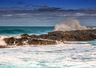 Waves breaking at rocks of the Indian Ocean at the Wild Coast of South Africa with cloudy sky