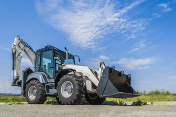 The new tractor is on the road in the city, a clear day with blue sky.