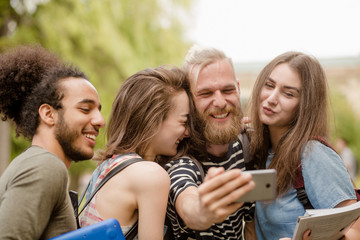 Fototapeta premium University students laughing making selfie shots. Young male and female happily smiling making photo on phone camera.