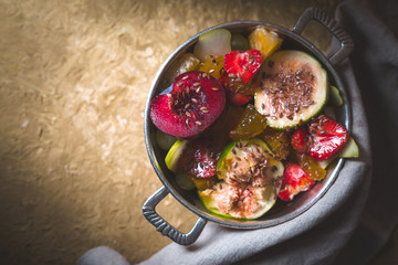 Fruit salad with figs, plum and pear in a tin bowl