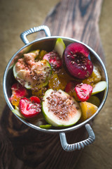 Fruit salad with flax seeds in a tin bowl on a wooden stand
