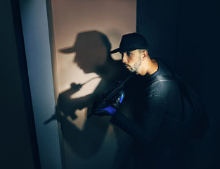Male thief with gun in house