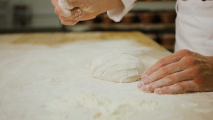 Close up shot of man hands making breads from the dough in the modern bakery background.
