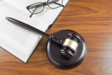 Judge gavel with sound board, open book and glasses on a wooden desk, top view from above, lawyers working place with justice symbols, concept for law and court, copy space