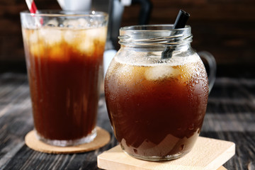 Jar and glass with cold brew coffee on wooden table