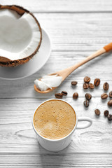 Cup of tasty coconut coffee and nut on wooden table