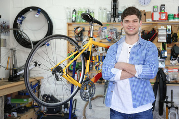 Fototapeta na wymiar Young man working in bicycle repair shop