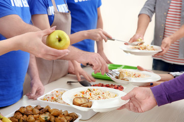Fototapeta na wymiar Young volunteers serving food to homeless people, closeup
