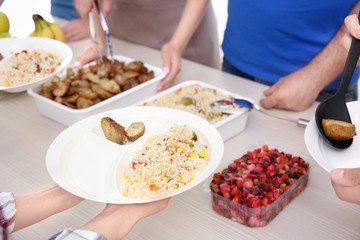 Young volunteers serving food to homeless people, closeup