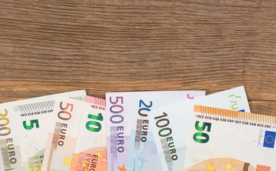 Lots of euro bills on wooden background.