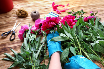 Florist making bouquet of beautiful peonies in flower shop