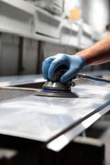 Man using orbital sander to prepare a metal panel