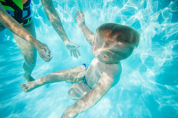 Mother or instructor teaching little boy to swim underwater