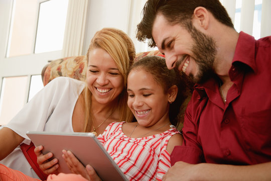 Happy Family Laughing Looking At Video On Tablet Computer