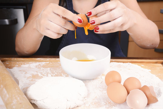 Woman breaking an egg into bowl.