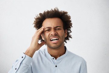 Picture of stressed young unshaven Afro-American employee in formal shirt having painful look,...