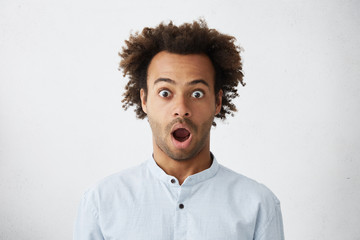 Shock and surprise. Studio portrait of surprised forgetful young man opening mouth widely and...