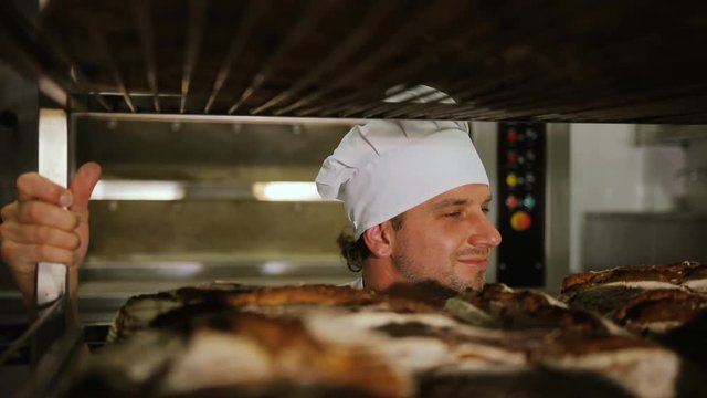 Portrait of young attractive baker man prouding of his handmade bread in the bakery. Close up.