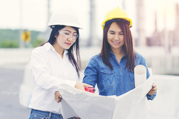 Women Engineer Holding Blueprint,Hanging Radio Communication at Outdoor Workplace for Inspection and Consult a Construction Project. Working at site to Measure Construction Workers - Engineer Concept