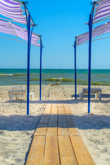 The path of wooden planks on the beach goes to the sea