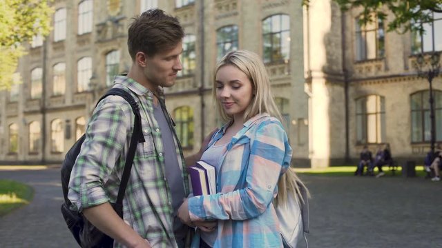 Handsome young man flirting with pretty blonde near college, students, meeting
