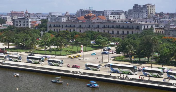A slowly moving aerial dolly establishing shot of traffic and buildings on the Avenida del Puerto in downtown Havana, Cuba.  	