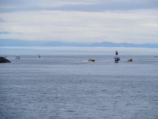 Little Motor boats in the blue ocean bay by the lighthouse with mountains in the back